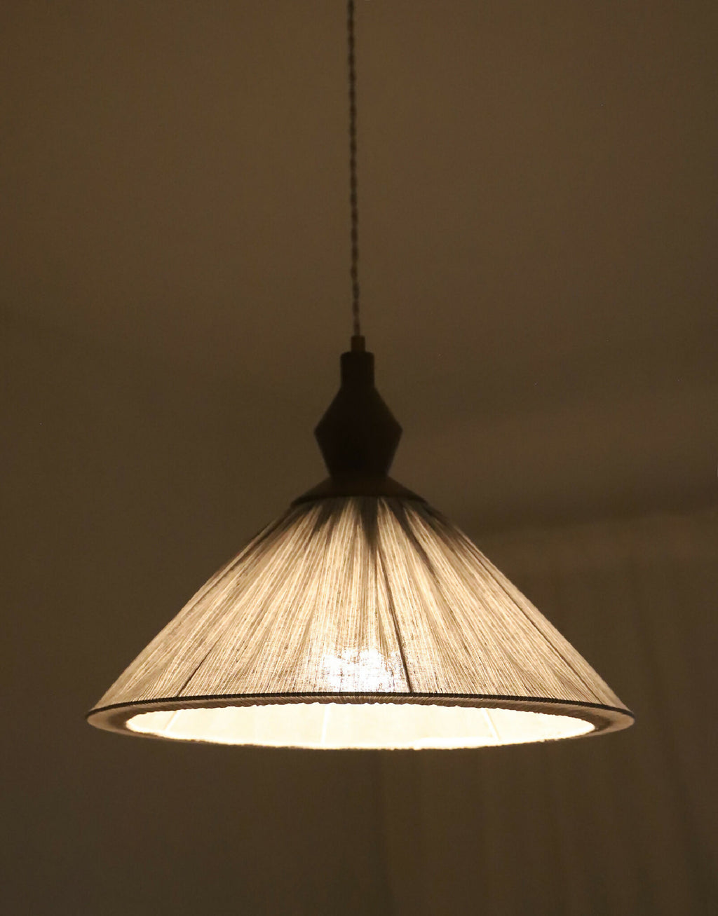 Abat-jour plissé à fines rayures avec structure intérieure, lumière allumée.
