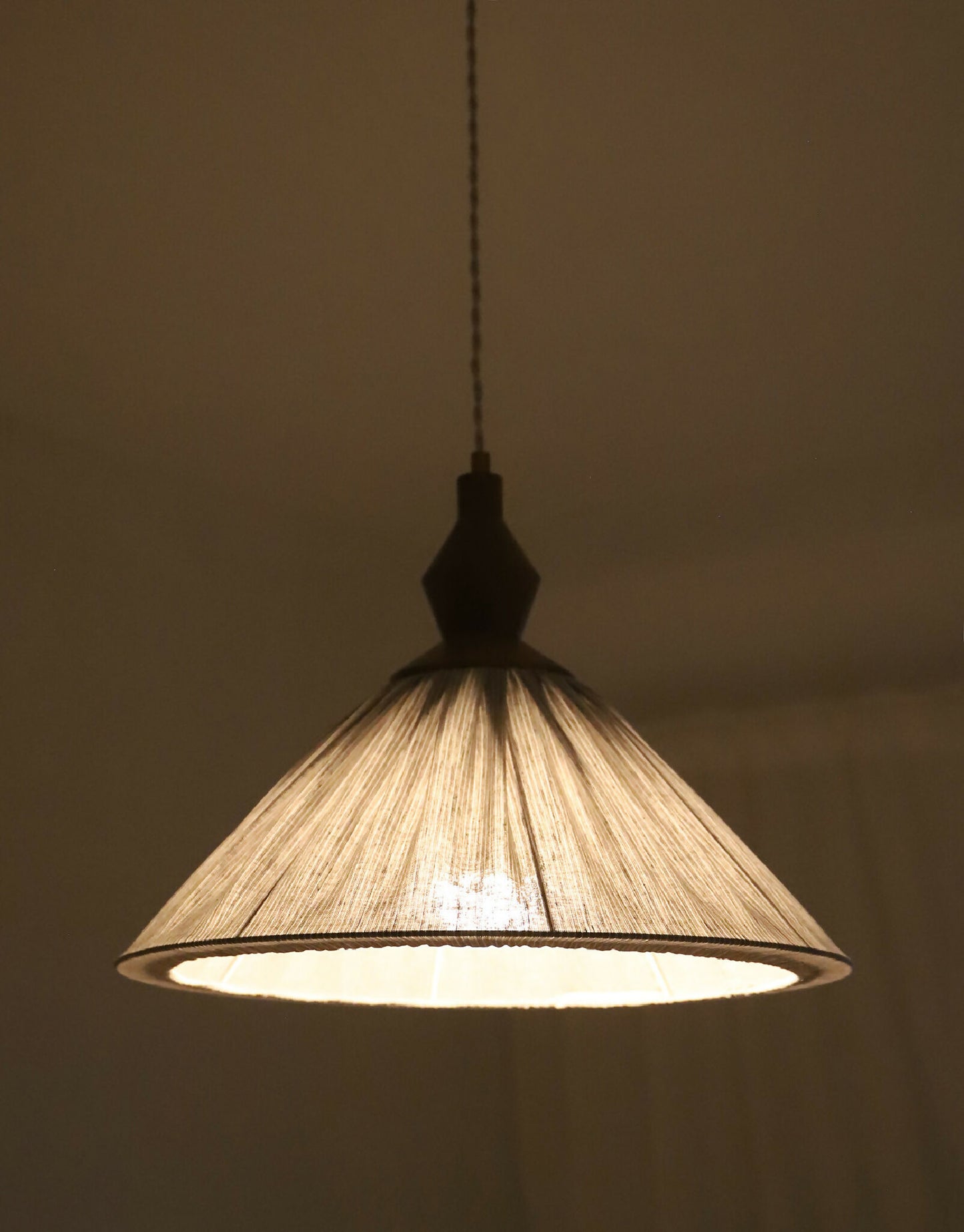 Abat-jour plissé à fines rayures avec structure intérieure, lumière allumée.