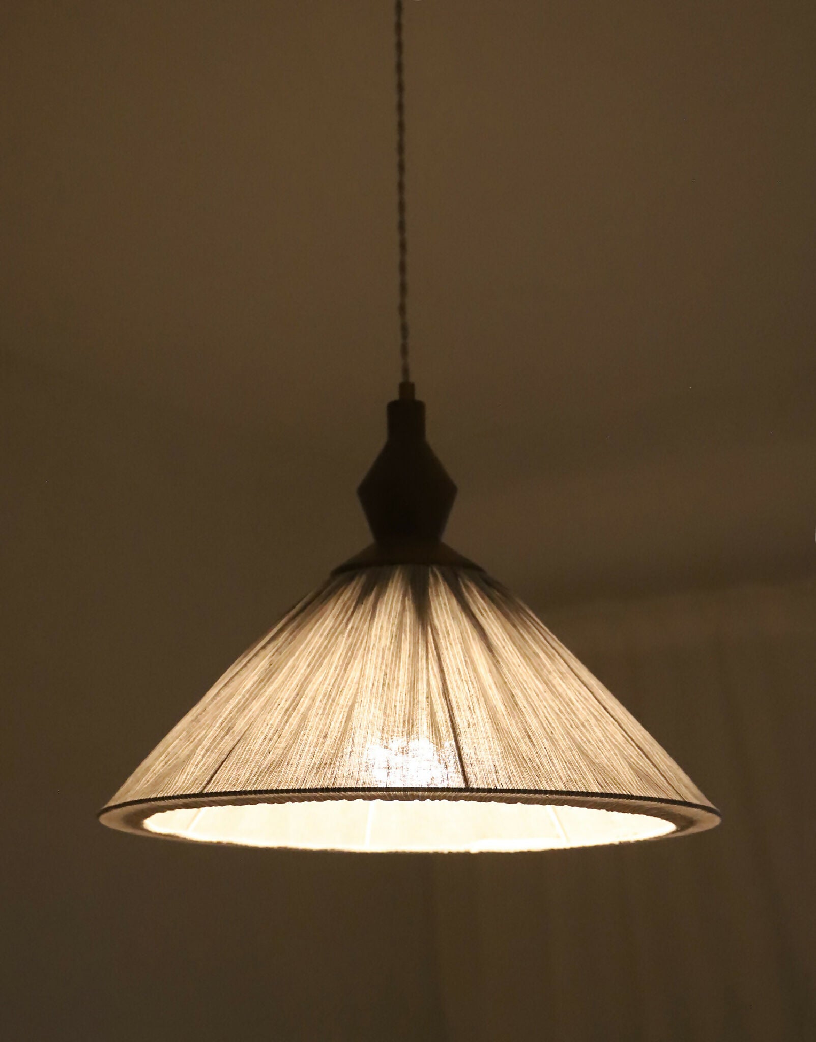 Abat-jour plissé à fines rayures avec structure intérieure, lumière allumée.