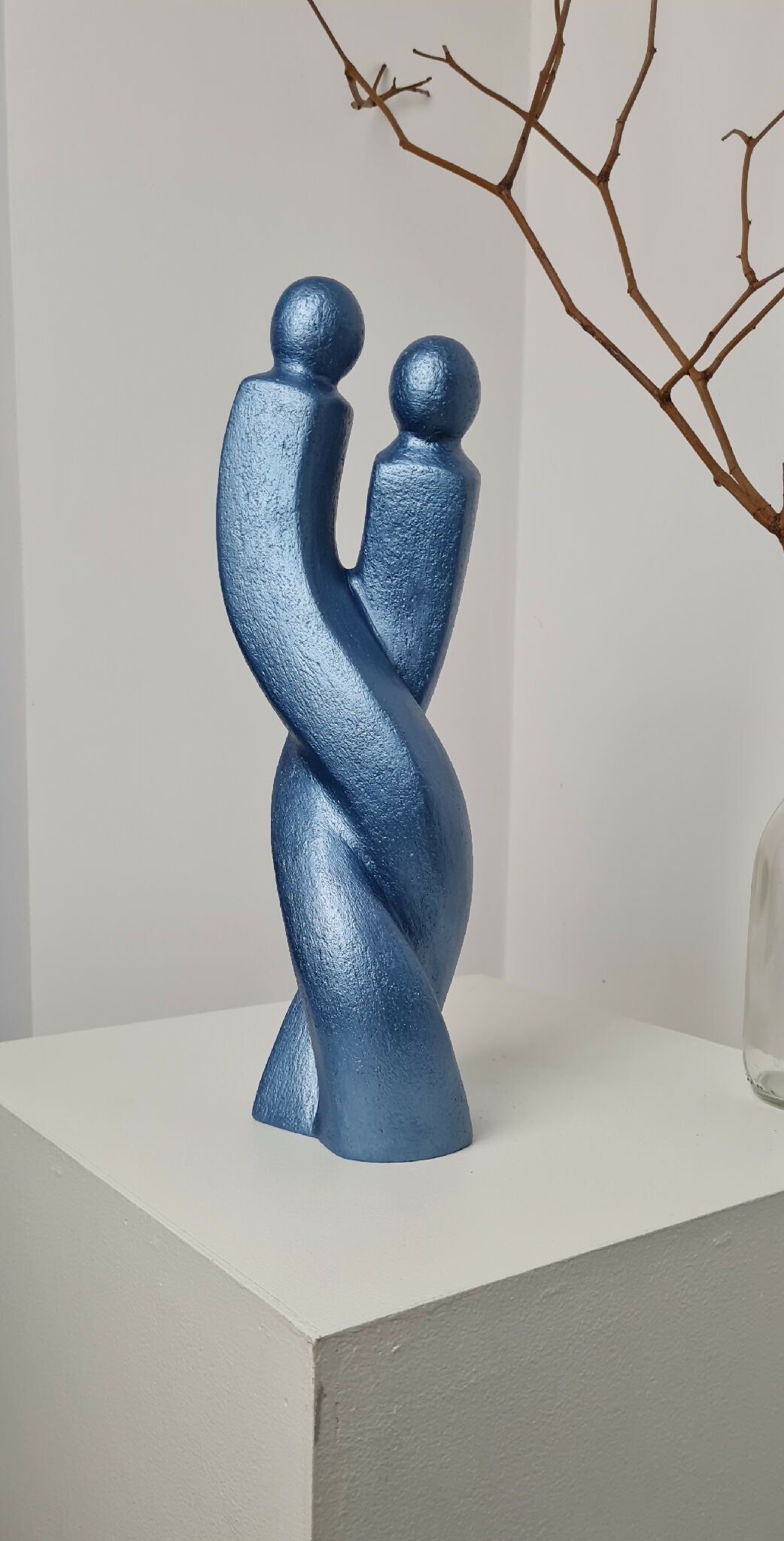 Sculpture de couple bleue sur socle, silhouettes enlacées, vue de trois-quarts