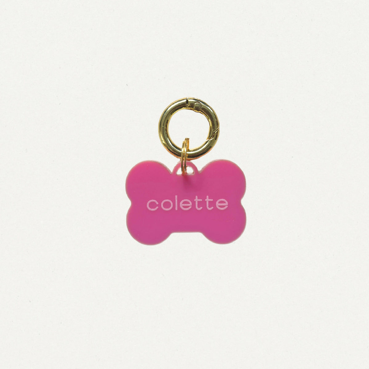 Médaille totem en forme d’os rose, anneau doré et inscription « colette ».