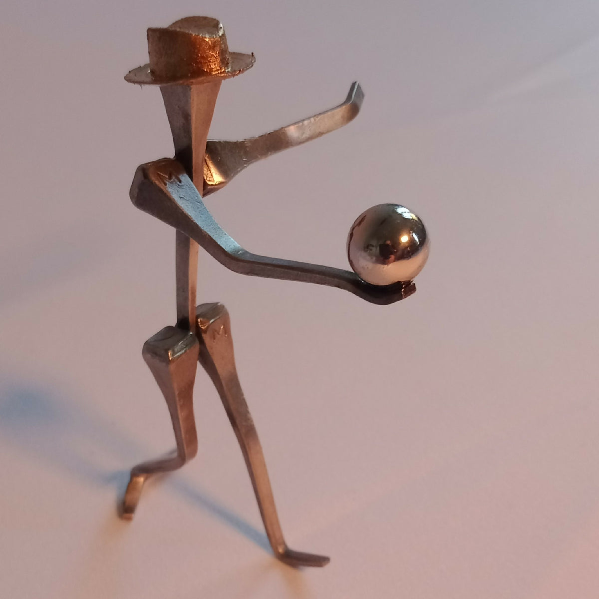 Figurine en métal : petit personnage doré tenant une boule chromée