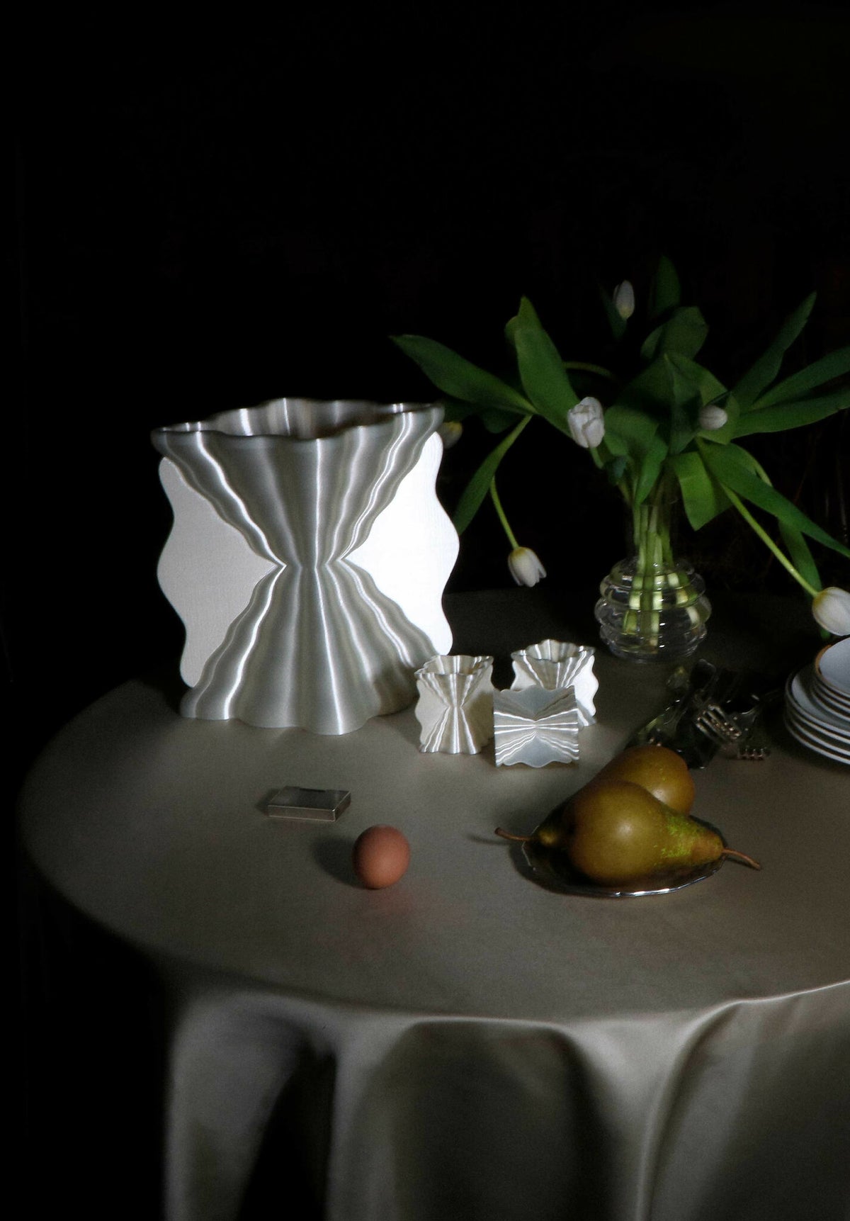 Lampe argentée à abat-jour ondulé, lumière allumée sur table.