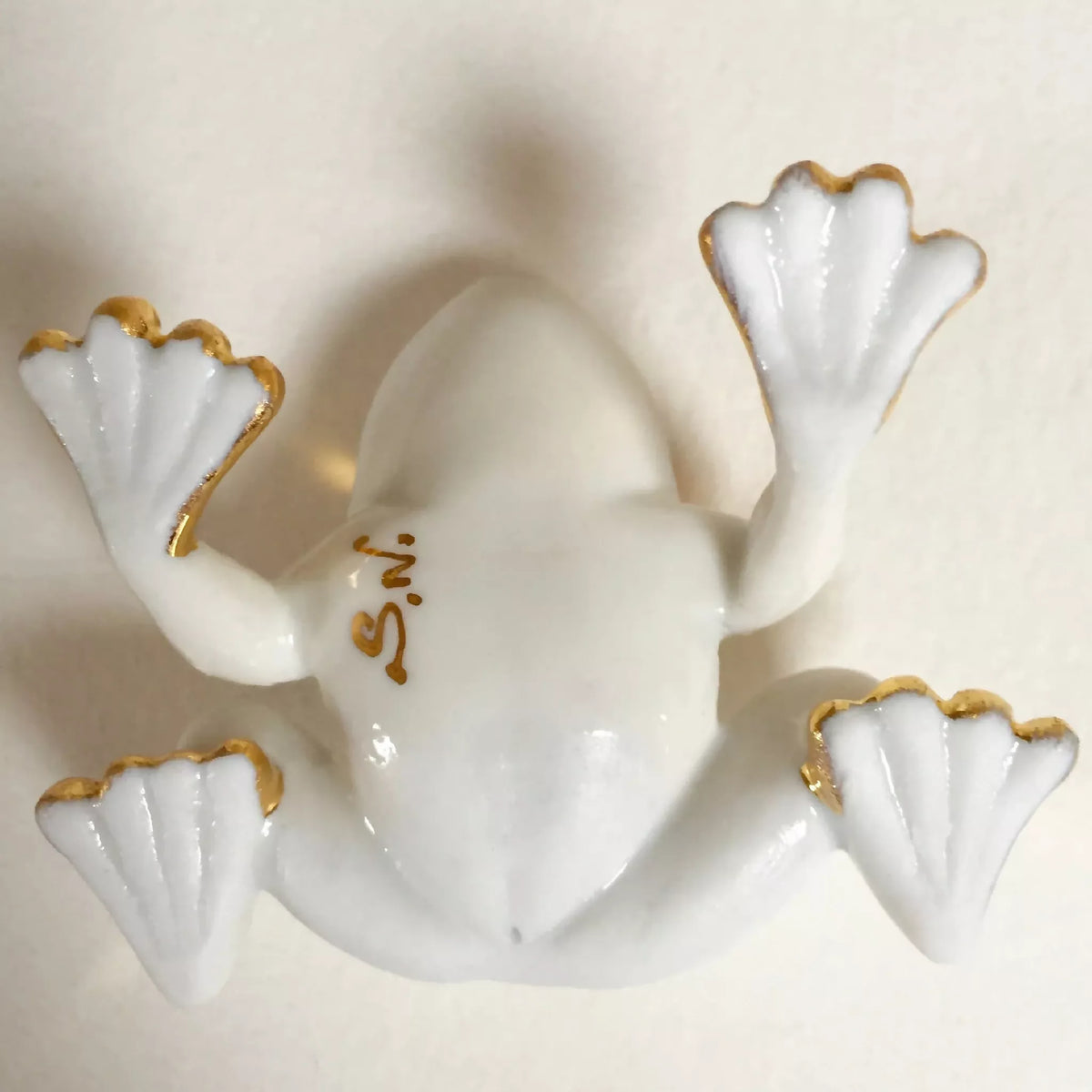 Figurine de grenouille en porcelaine blanche, pattes sculptées et bordures dorées