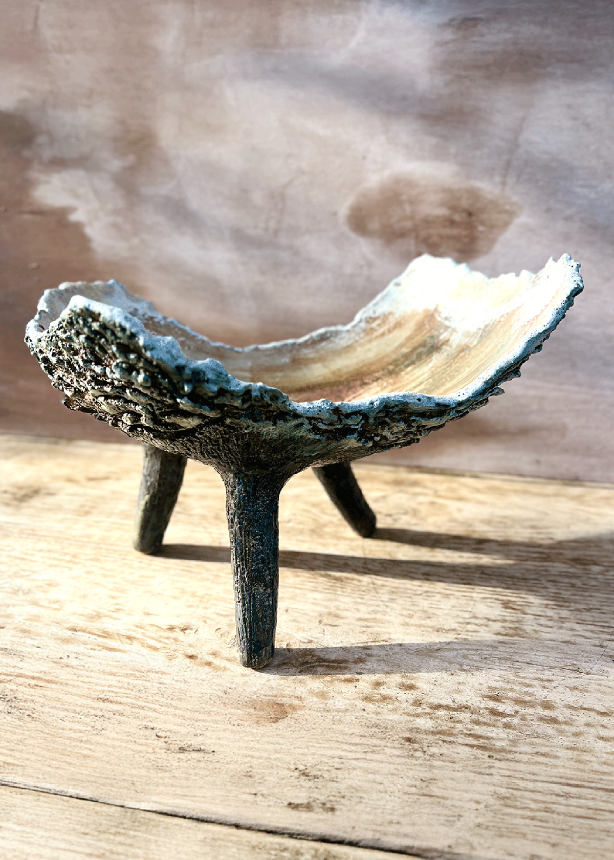 Coupe ou jardinière tripode en céramique patinée, intérieur clair beige, trois pieds inclinés.