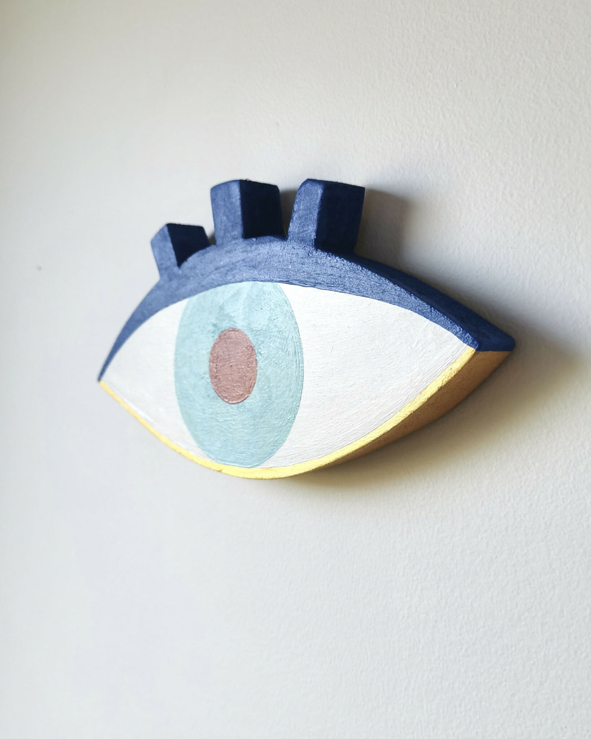 Plaque œil en bois bleue, iris bleu clair, pupille rouge et cerne jaune.