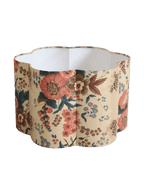 Abat-jour forme fleur, fond crème et fleurs rouges, bleues et brunes, intérieur blanc.