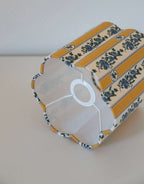 Abat-jour forme fleur en tissu jaune à rayures verticales et motifs bleus.