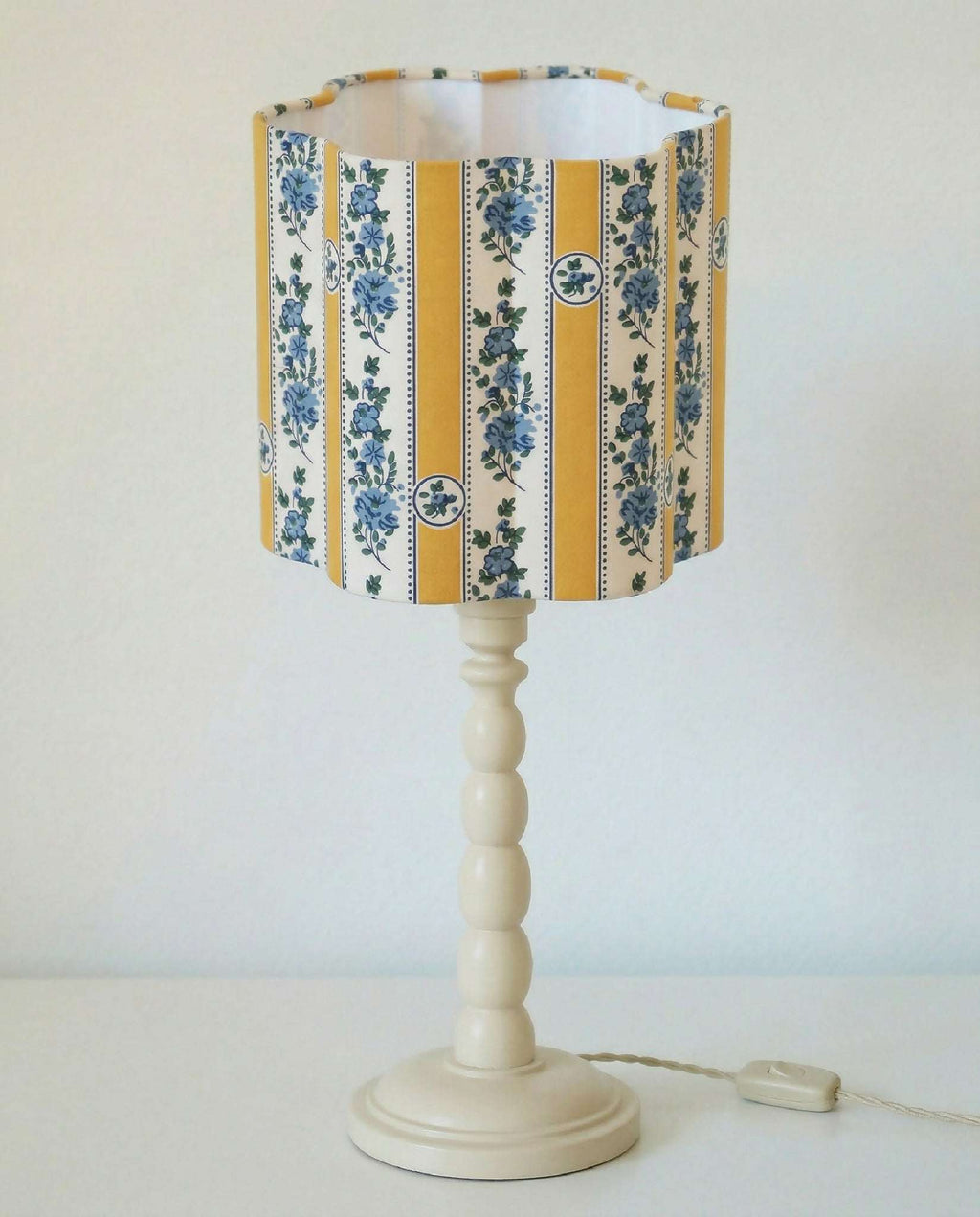 Abat-jour forme fleur en tissu rayé jaune et bleu, sur pied blanc à boules.