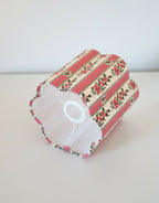 Abat-jour forme fleur rayé rose, motifs floraux, vue de profil avec intérieur blanc.