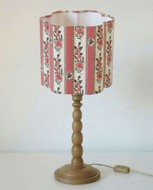 Abat-jour forme fleur à motifs floraux et rayures roses, sur pied en bois.