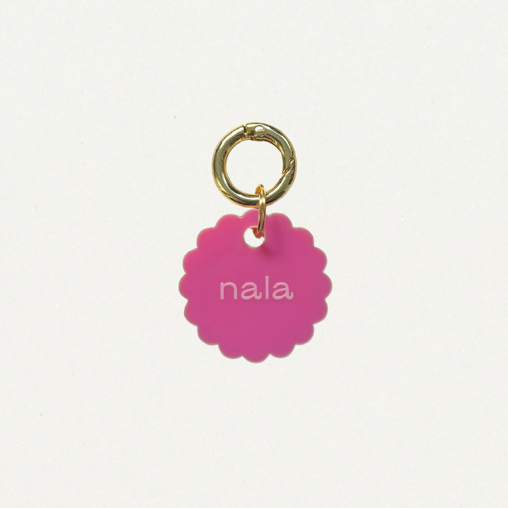 Médaille Bloom en émail rose, anneau doré, texte « nala » au centre.