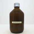 Flacon de shampoing en verre brun, bouchon cannelé et étiquette rectangulaire blanche.