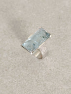 Bague en topaze bleu clair rectangulaire, monture argent, vue de profil.