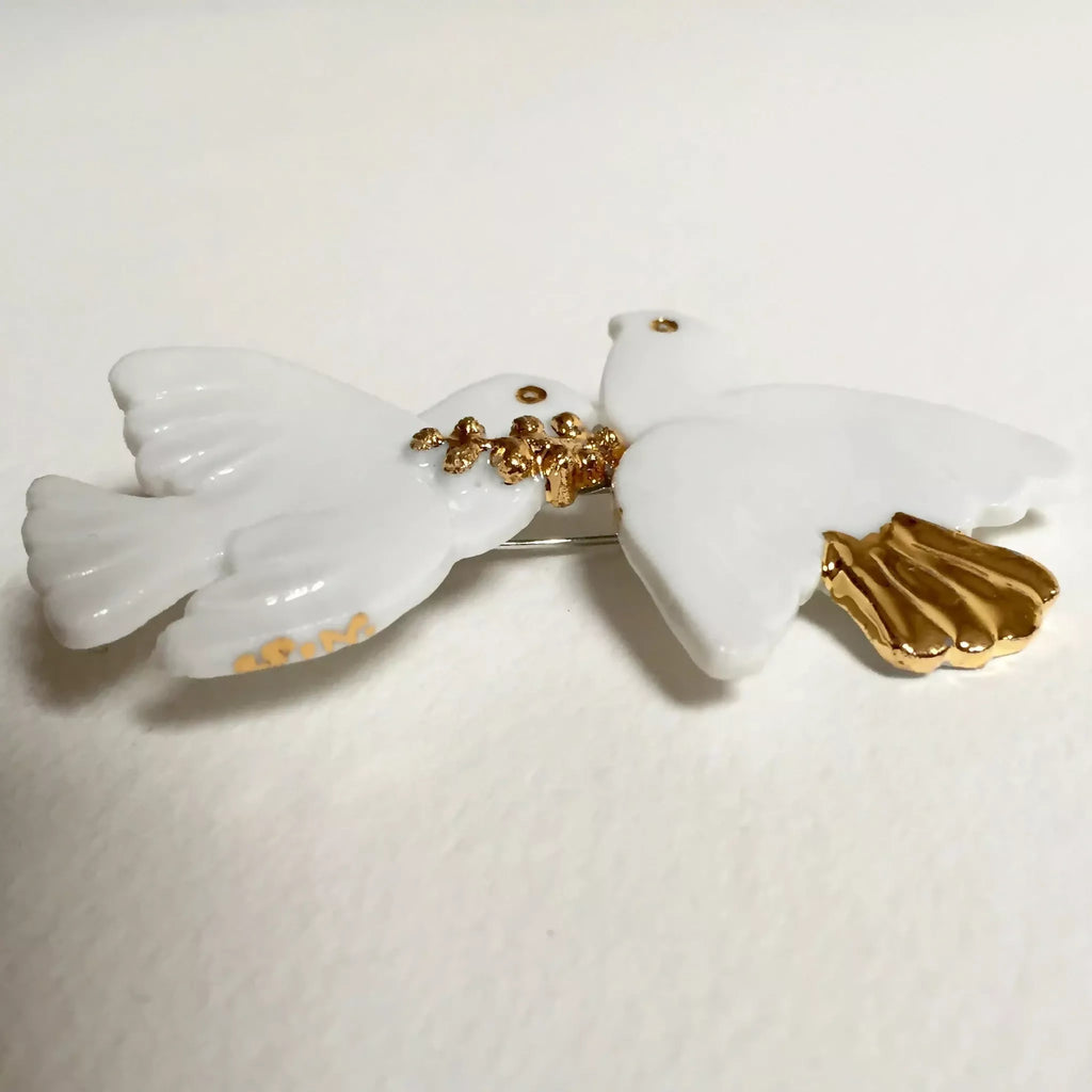 Broche colombes blanches, motif doré au centre et épingle arrière visible.