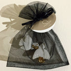 Broche colombes blanches à accents dorés, portée sur sachet en organza.