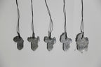 Lot de pendentifs gris en forme de feuille d’arbre, sur cordons noirs.