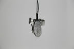 Pendentif gris en forme de feuille d’arbre, vue de profil, sur cordon noir.