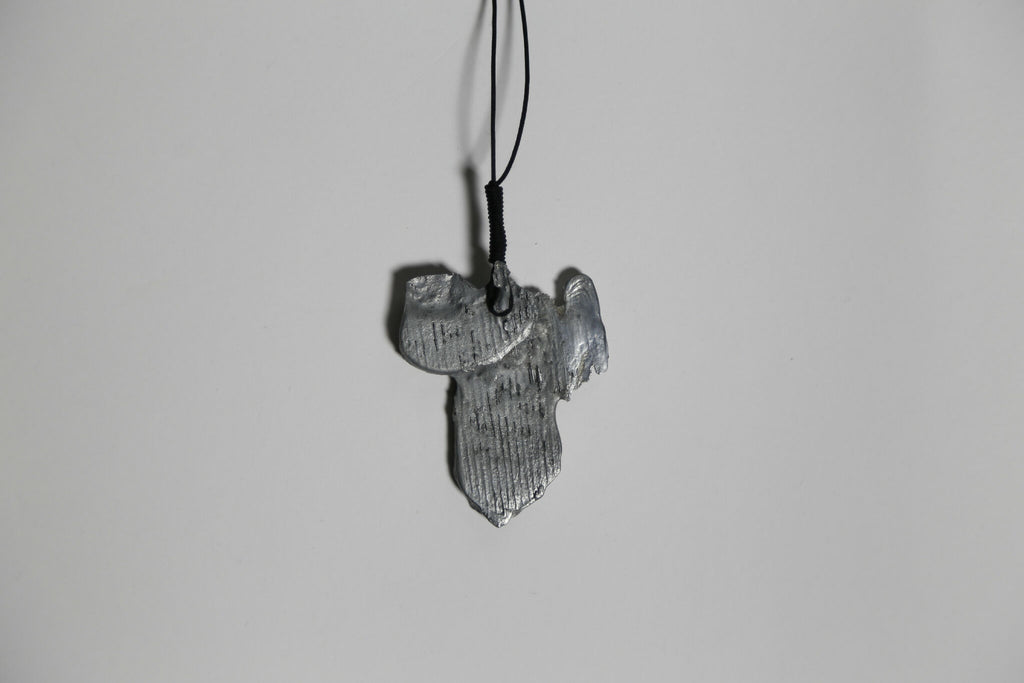Pendentif argenté-gris en forme de feuille, détail de texture, sur cordon.