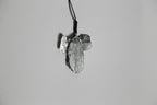 Pendentif gris argenté en forme de feuille d’arbre, vue rapprochée, sur cordon.