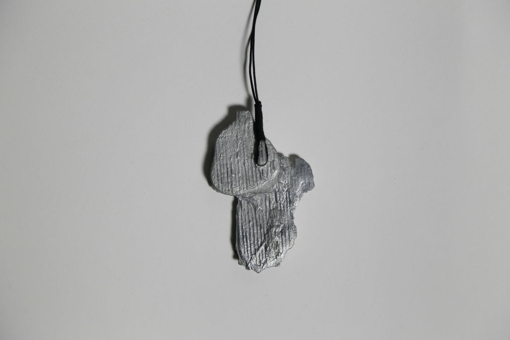 Pendentif gris en forme de feuille, texture nervurée, sur cordon noir.