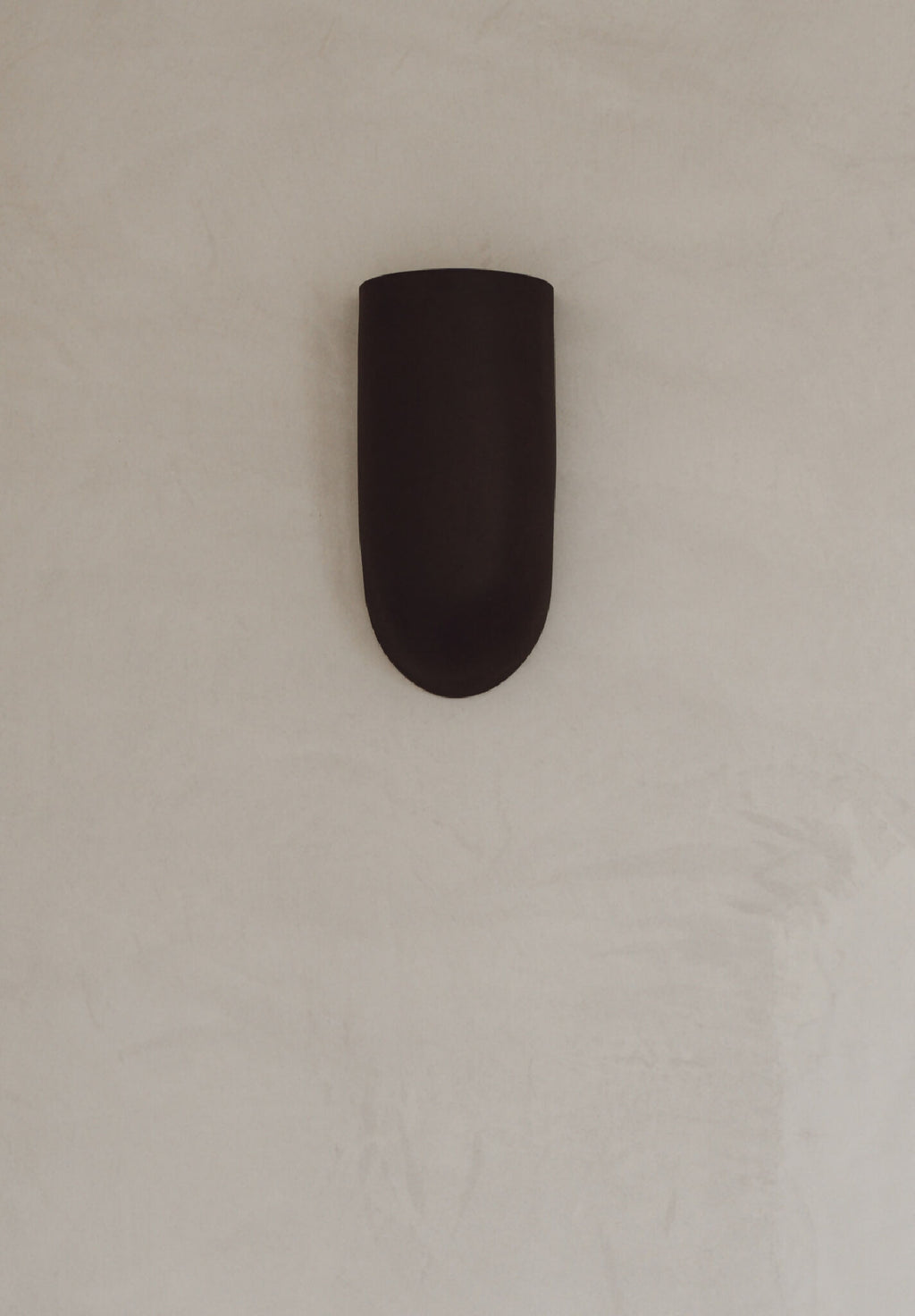 Applique murale en céramique marron, vue rapprochée, éclairage intégré vers le bas.