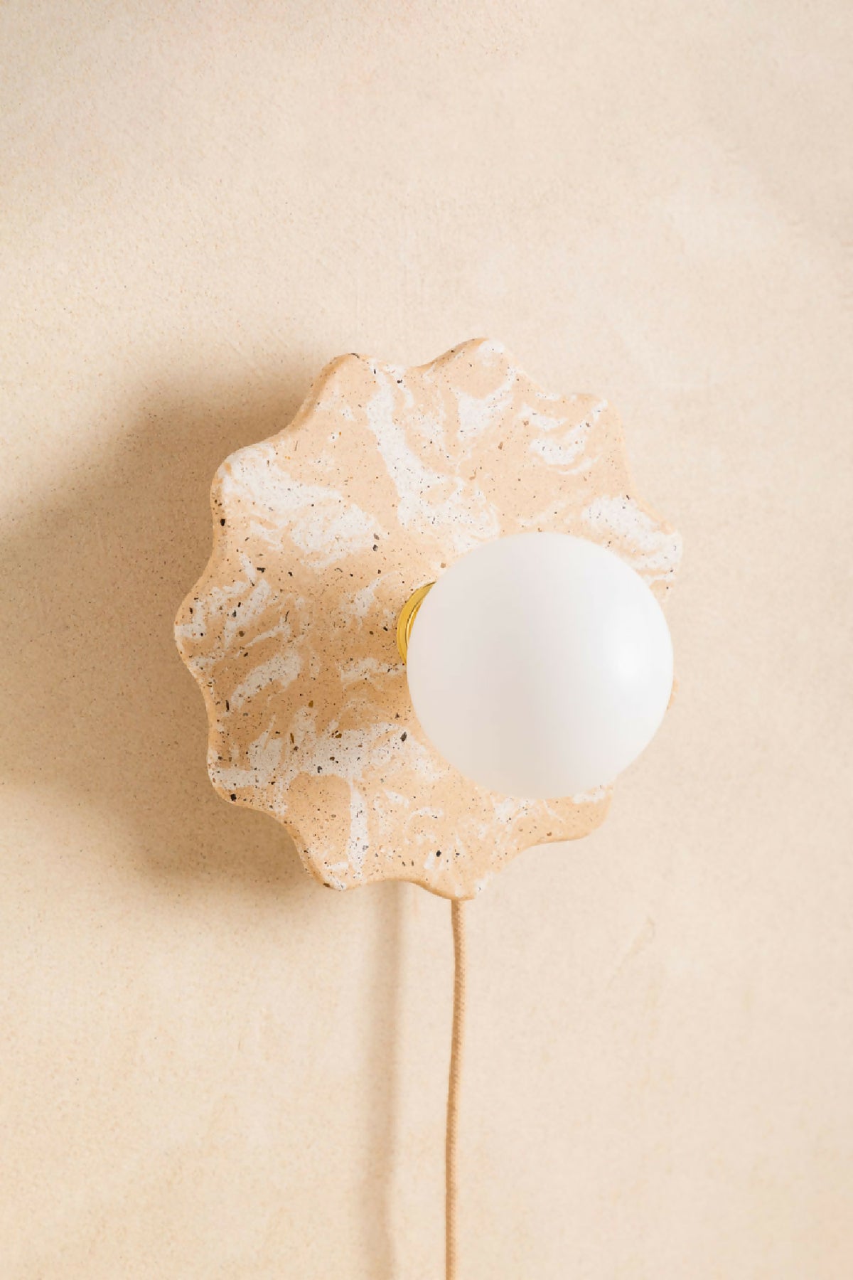 Applique murale en forme de fleur beige clair tachetée, globe blanc et câble.