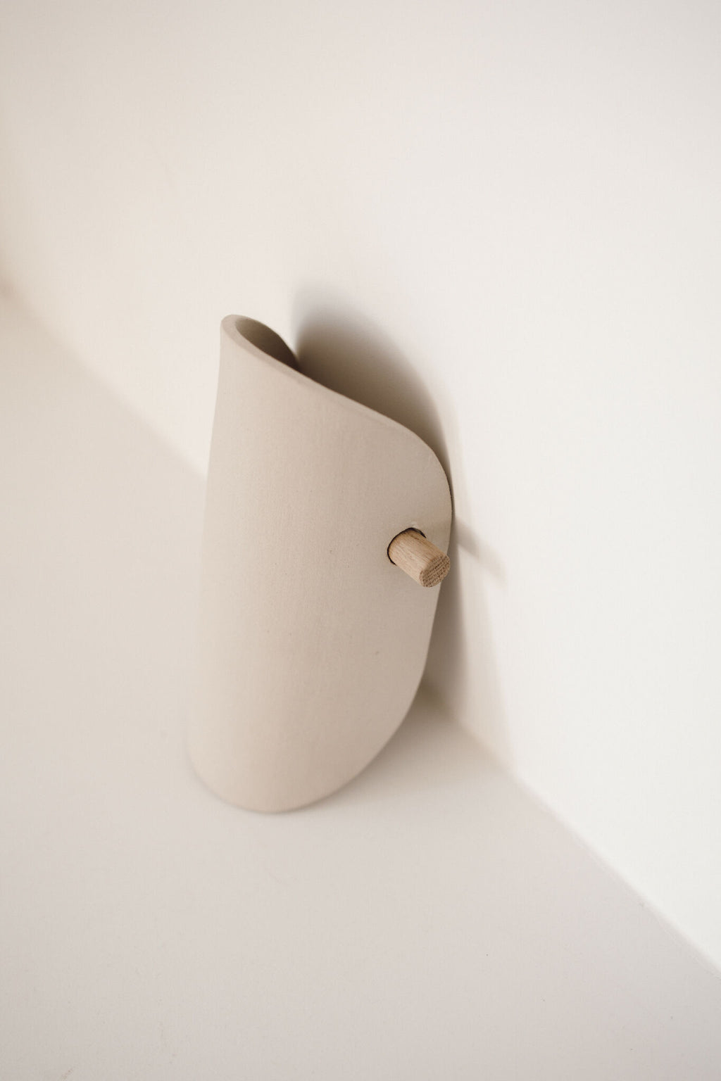 Applique murale en céramique beige, forme arrondie, fixation avec bouton en bois