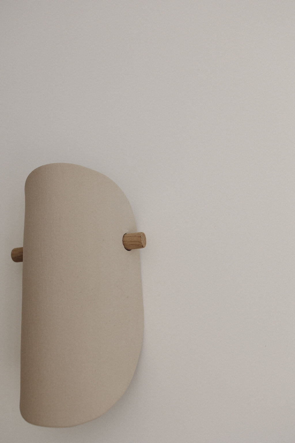 Applique murale en céramique beige, vue de côté, fixation en bois