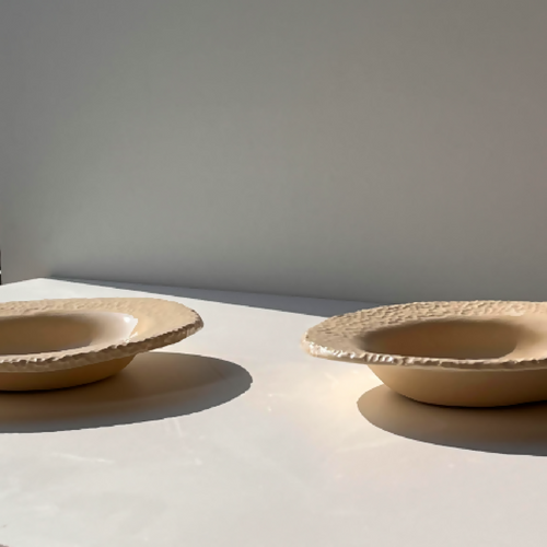Deux assiettes beige texturées, bord dentelé, vues de côté