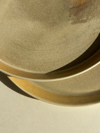 Assiette sable céramique beige, gros plan du bord ondulé et surface granuleuse