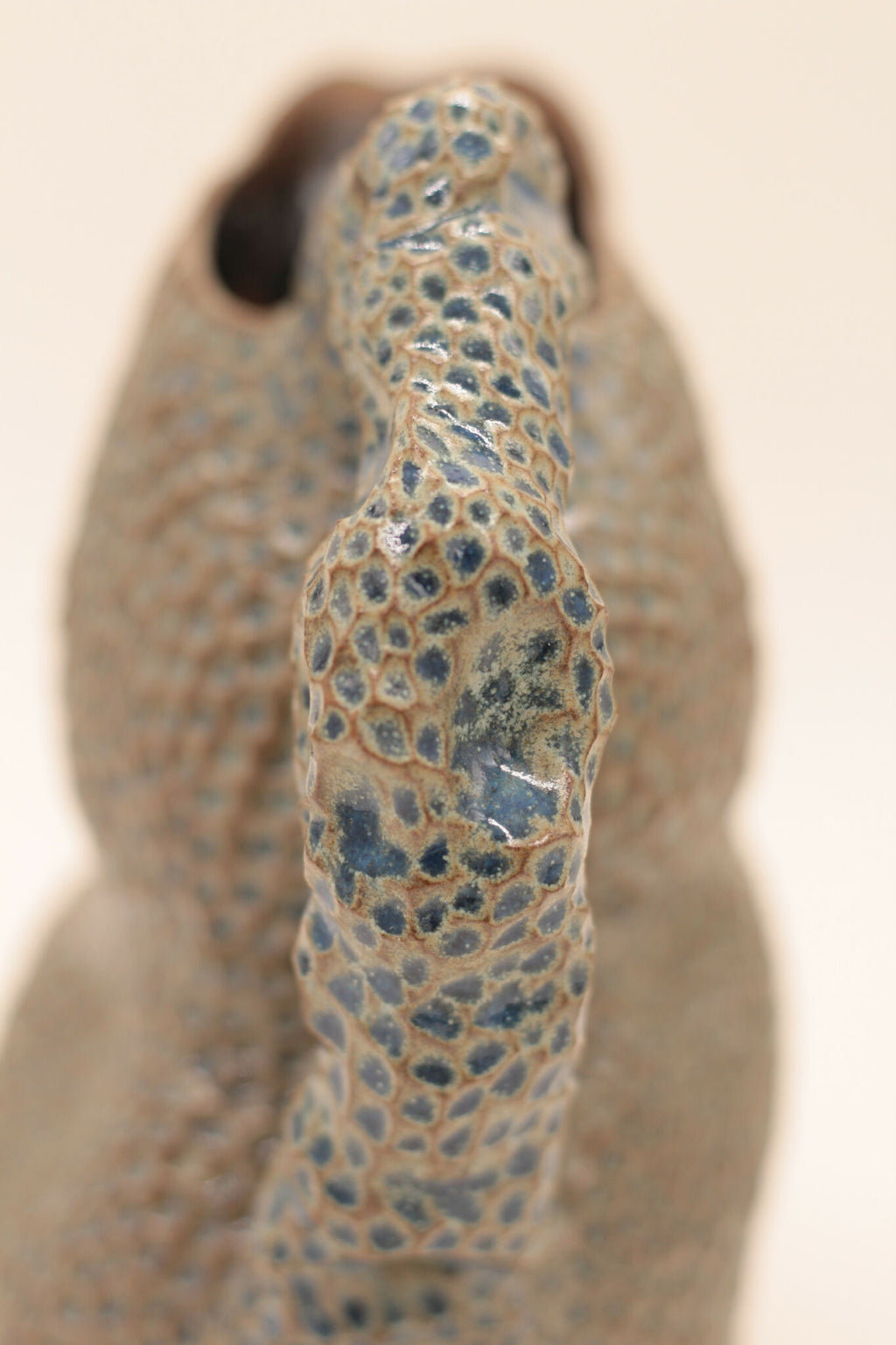 Pichet en céramique bleu moucheté, gros plan du bec et du motif granuleux.
