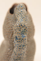 Pichet en céramique bleu moucheté, gros plan du bec et du motif granuleux.