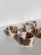 Lot de tasses en céramique blanches à motifs abstraits marron, plusieurs unités sur table