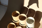 Lot de tasses à expresso en céramique beige et nacrée, empilées.