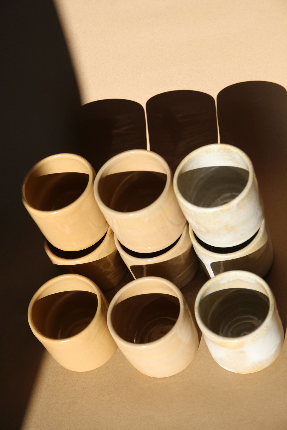 Lot de tasses à expresso en céramique beige et nacrée, vues en perspective.