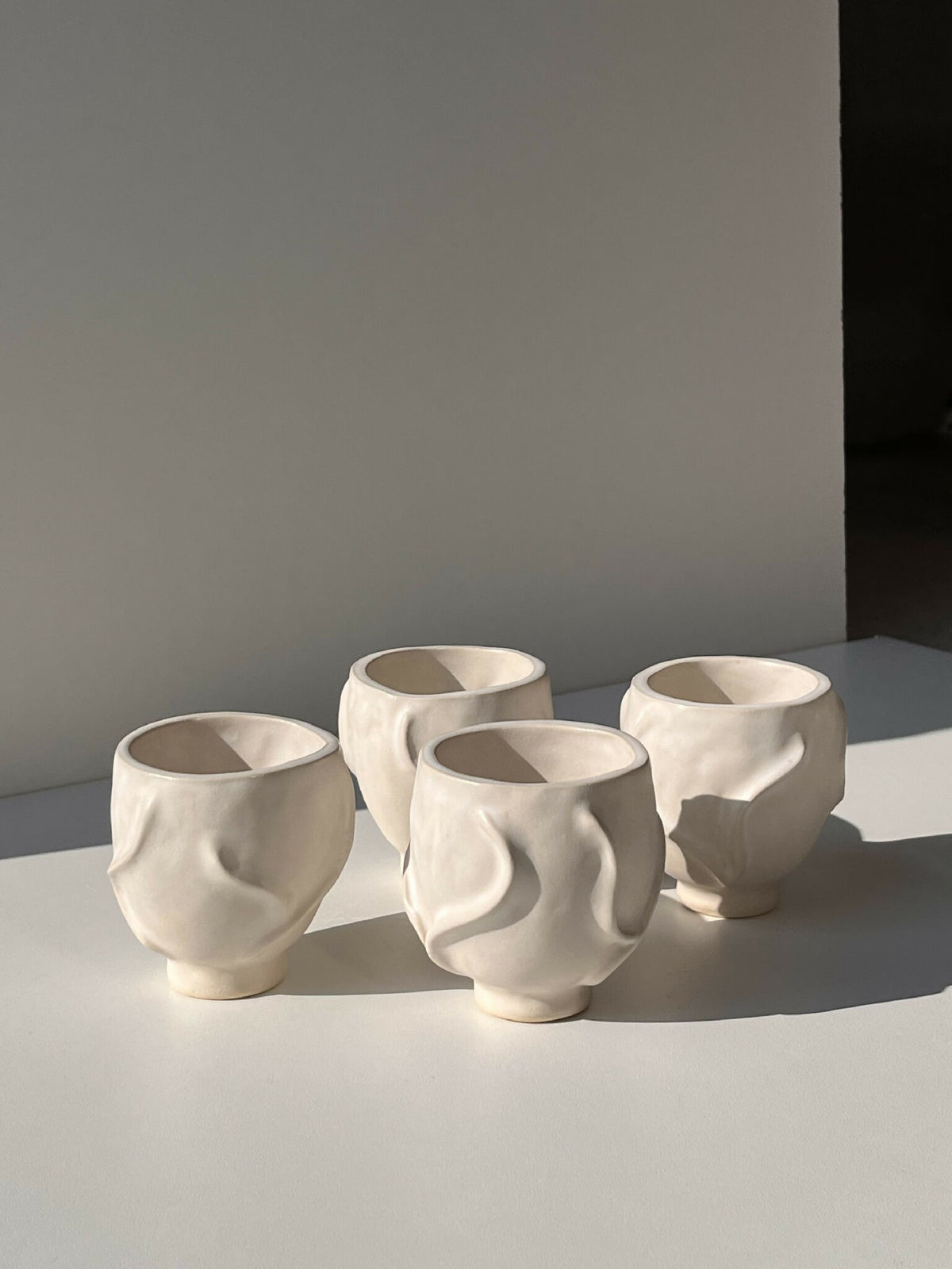 Lot de 4 tasses en céramique blanche à relief ondulé, alignées