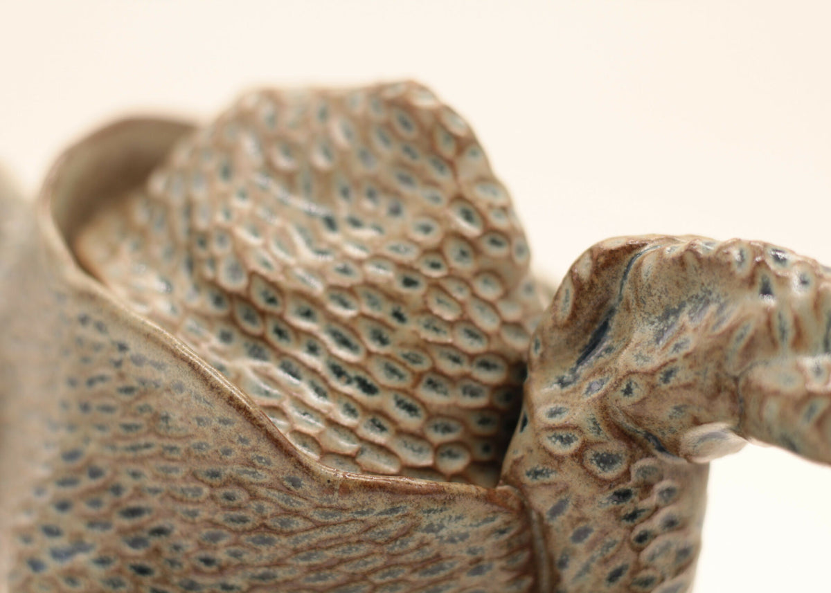 Théière en céramique bleu-gris à texture, vue rapprochée du bec et de l’anse