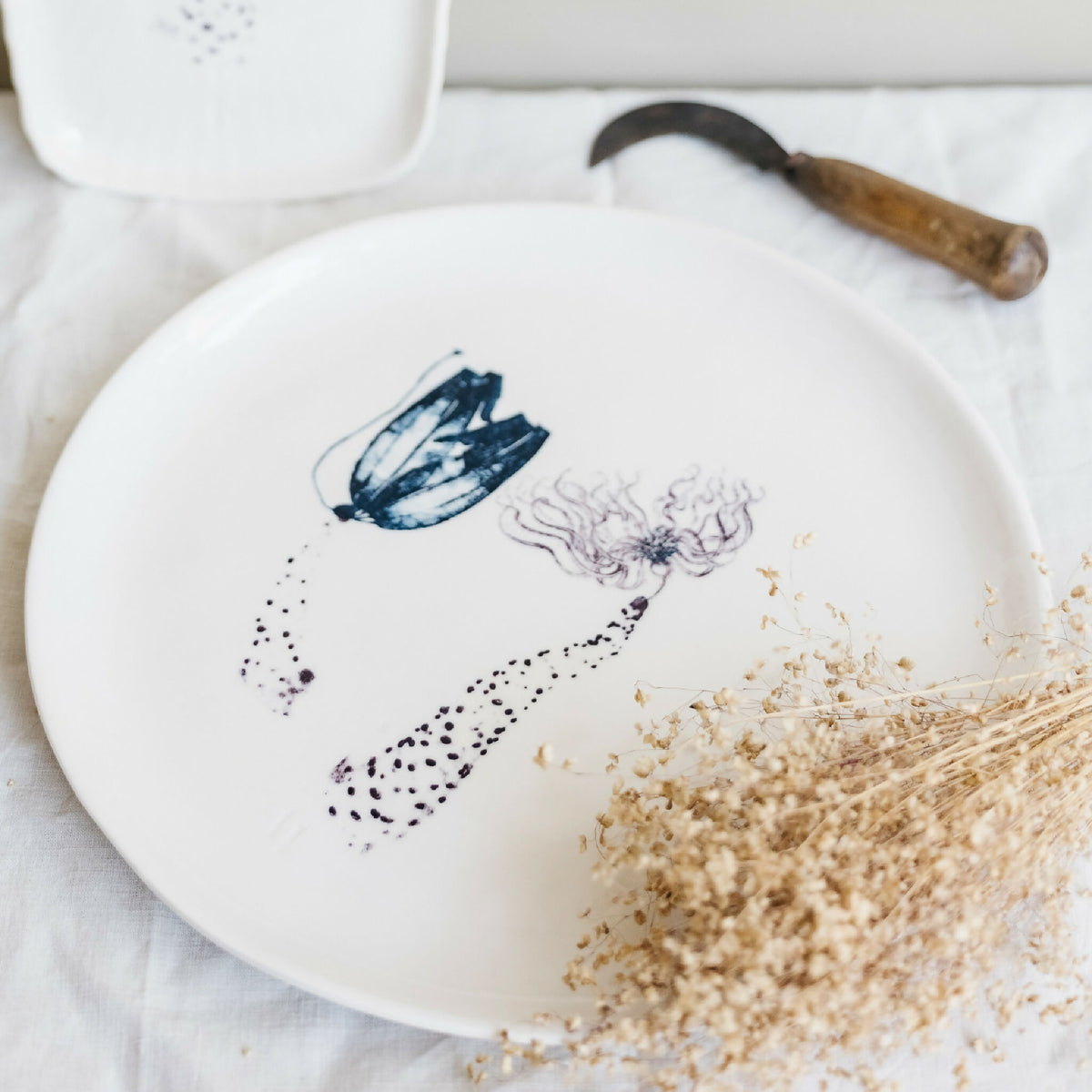 Plat rond en porcelaine blanche fait main, décor abstrait bleu-violet et beige.