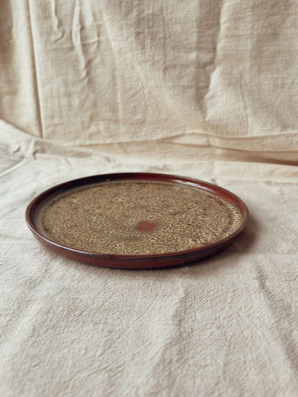Assiette ronde en céramique beige moucheté, liseré bordeaux, style classique Algue