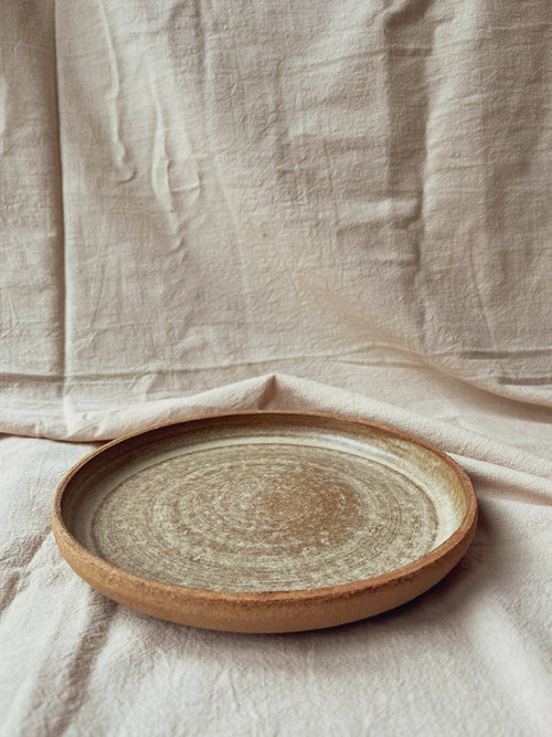Assiette creuse en céramique beige à bord brun, vue de dessus, finition texturée