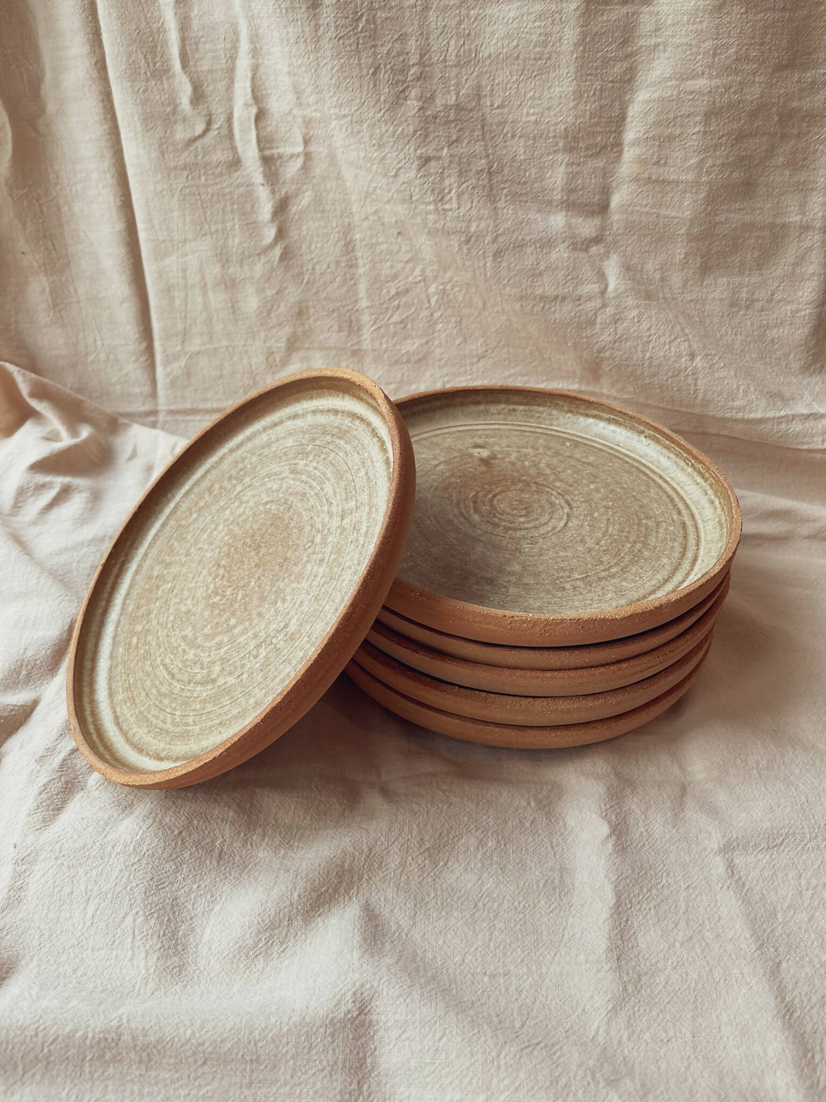 Assiettes creuses en céramique beige à bord brun, pile avec une assiette soulevée