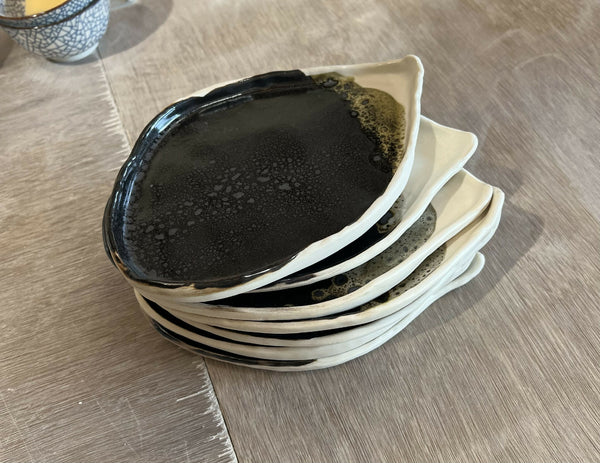 Petite assiette BT noirâtre à bord blanc, motif en relief, empilée avec plusieurs pièces