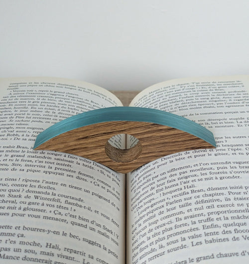 Marque-page en bois bleu turquoise sur livre ouvert, motif ajouré