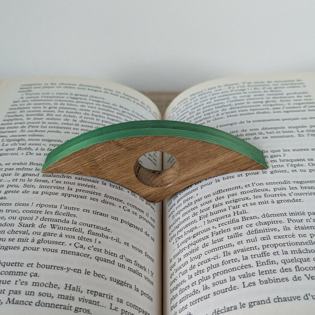 Marque-page en bois à bande verte, posé sur un livre ouvert.