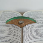 Marque-page en bois à bande verte, posé sur un livre ouvert.