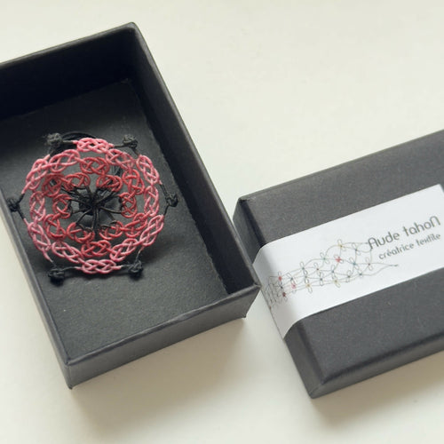 Bague en soie trèfle rouge présentée dans une boîte noire, motif ajouré
