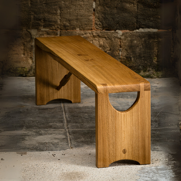 Banc en bois clair avec plateau rectangulaire et ouverture demi-lune sur le piètement.