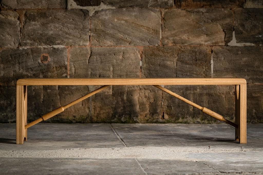 Banc en bois clair avec cadre inférieur en bois et renforts inclinés.