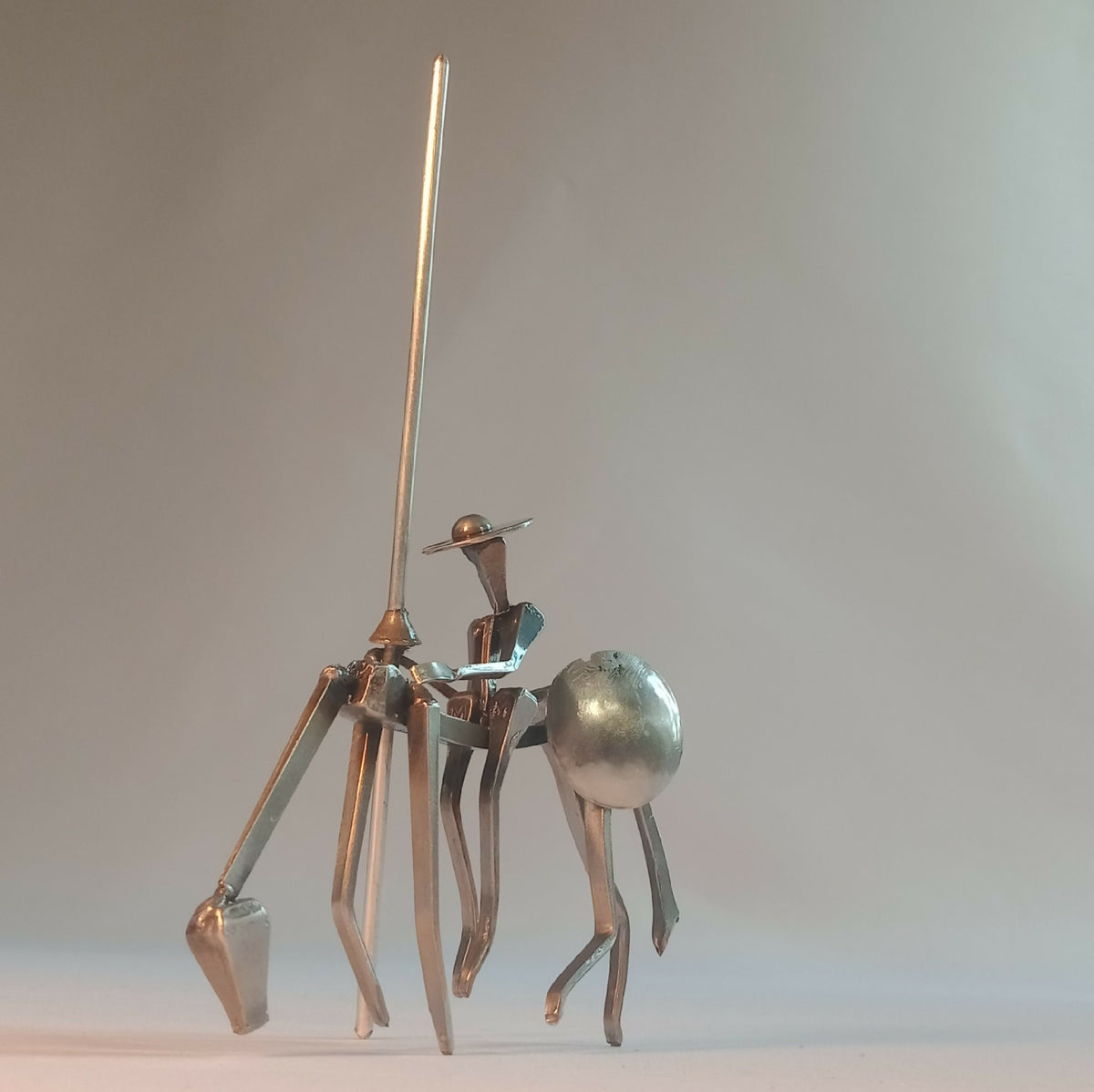 Sculpture en acier : chevalier debout et personnage assis, socle et livre ouvert.